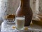 A glass of milk, a bowl of cookies, an earthenware jug, and old books on a Lacy white tablecloth