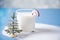 Glass of milk, candy cane, miniature christmas tree on the blue background
