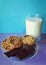 Glass of milk, cookies and chocolate on the saucer on purple surface and on blue background