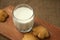 A glass of milk with cookies on a wooden board on a background sacking, burlap