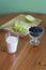 A glass of milk, a plate of apples, a bowl of blueberries on a green background