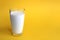 A glass of milk stands on a yellow background with a place for the text.