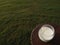 Glass of milk on table, top view on green grass field