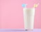 glass of milkshake with a straw on a pastel color wooden table isolated on pink. Copy space