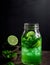 A glass of mint lime soda cocktail in a jar with a dark background