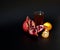 A glass of a mixture of fruit juices on a black background, next to pieces of ripe tangerine and a broken pomegranate fruit