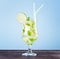 Glass of mojito cocktail on pastel blue background