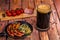 Glass mug with dark beer with fried sausages