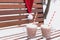 Glass mugs, cups with hot chocolate, cocoa, marshmallows. Santa Claus hat. Winter snow covered park bench. Striped red paper
