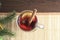 A glass of mulled wine is on a bamboo napkin. A sprig of Holly. New year`s drink