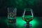Glass o whisky with ice and wineglass of cognac on green bokeh background
