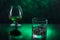 Glass o whisky with ice and wineglass of cognac on green bokeh background