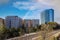 Glass office buildings and apartments along a side a set of railroad tracks with blue sky and powerful clouds and a rainbow