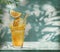 Glass of orange juice with orange splash on the table and stucco pattern wall with leaf shadows at the background