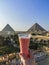 A glass of orange juice overlooking the Great Pyramid of Giza and the Pyramid of Khafre