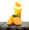 Glass of orange juice with splash and oranges on wooden table