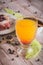 Glass with orange juice on wooden board with whole camembert