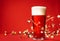 Glass of of pale lager beer or ale with christmas lights and tinsel on red background