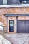 Glass paned front door with wreath beside garage door of home with stone wall