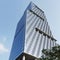 Glass-paneled office building. The glass is blue. Sky background. View from below