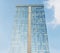 Glass-paneled office building. The glass is blue. Sky background. View from below