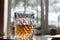 A glass patterned glass with whiskey or cognac stands on the table on a white background the glass is illuminated side