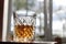 A glass patterned glass with whiskey or cognac stands on the table on a white background the glass is illuminated side