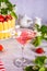 Glass of pink cocktail, cake with fresh strawberries with flowers branch of apple tree. Wedding or Valentines day romatic date