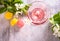 Glass of pink cocktail with flowers branch of apple tree and colorful macaroons. Wedding or Valentines day romatic date couple