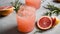 A glass of pink grapefruit juice with a sprig of rosemary