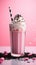 a glass of pink milkshake with whipped cream and black straw