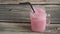 A glass of  pink milkshake on wood table