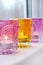 Glass pink and yellow candlesticks on white windowsill