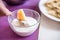 A glass plate of sour cream and a dumpling impaled on a fork