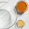 Glass plates with red lentils, sesame seeds and a large glass plate stand on wooden table