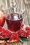 Glass of pomegranate juice with ripe fresh punica granatum fruits with leaves on wooden table