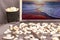 Glass with popcorn, seashells on a gray background, picture with evening sea landscape