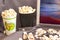 Glass with popcorn, seashells on a gray background, picture with evening sea landscape