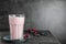 Glass of protein shake and berries on table against grey background