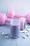 Glass of Protein Shake with milk and blueberries. Creatine capsules and pink dumbbells in background. Sport nutrition.