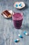 Glass of Protein Shake with milk and blueberries, Creatine capsules and Protein bar.