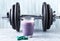 Glass of Protein Shake with milk and blueberries, L-Carnitine capsules and a dumbbell in background. Sports bodybuilding nutrition