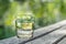 Glass of pure fresh water on the old tree stump. Green nature background