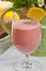 Glass of raspberry coconut smoothie with a slice of lemon
