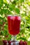 A glass of red cherry juice with ice cubes and cherries and red currants on a natural background