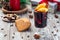 Glass of red glogg or mulled wine with orange slices and cinnamon stick, gingerbread cookies and gift box on background,