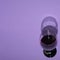 A glass of red wine that casts a shadow on a purple background. Minimal scene for wine lovers