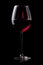 A glass with red wine is isolated on black background. Rose wine splashing in glassware.