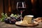 a glass of red wine next to a block of cheese on a rustic table