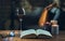 Glass of red wine, open book with candles in the background on wooden table